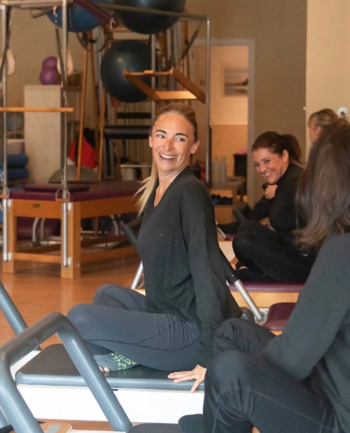 Alumnas sonriendo durante una clase de pilates en máquina